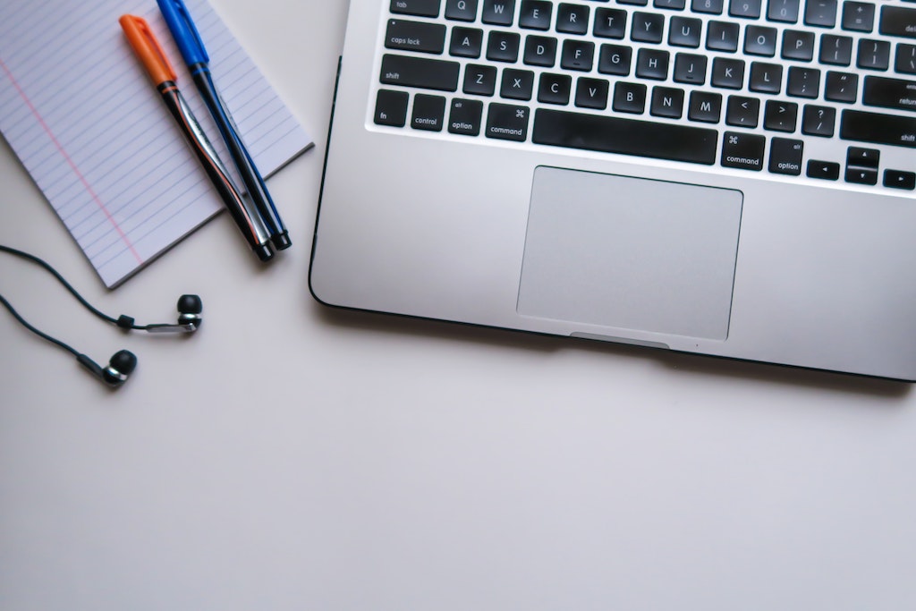 Laptop with pen and paper during online exam